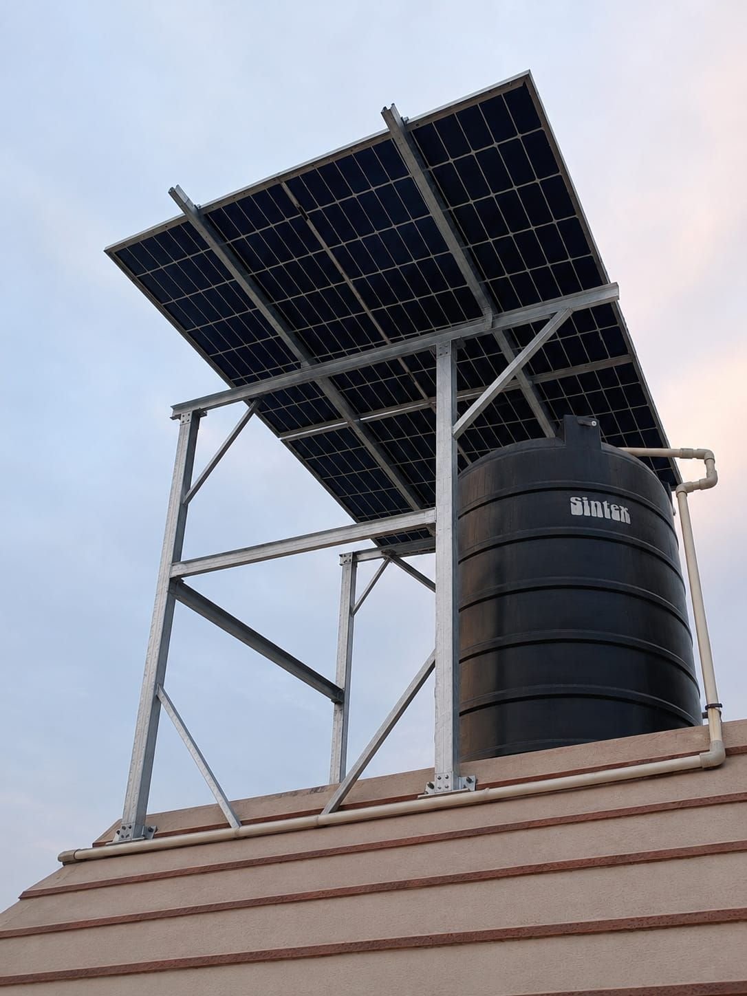 Solar panels mounted above a rooftop water tank